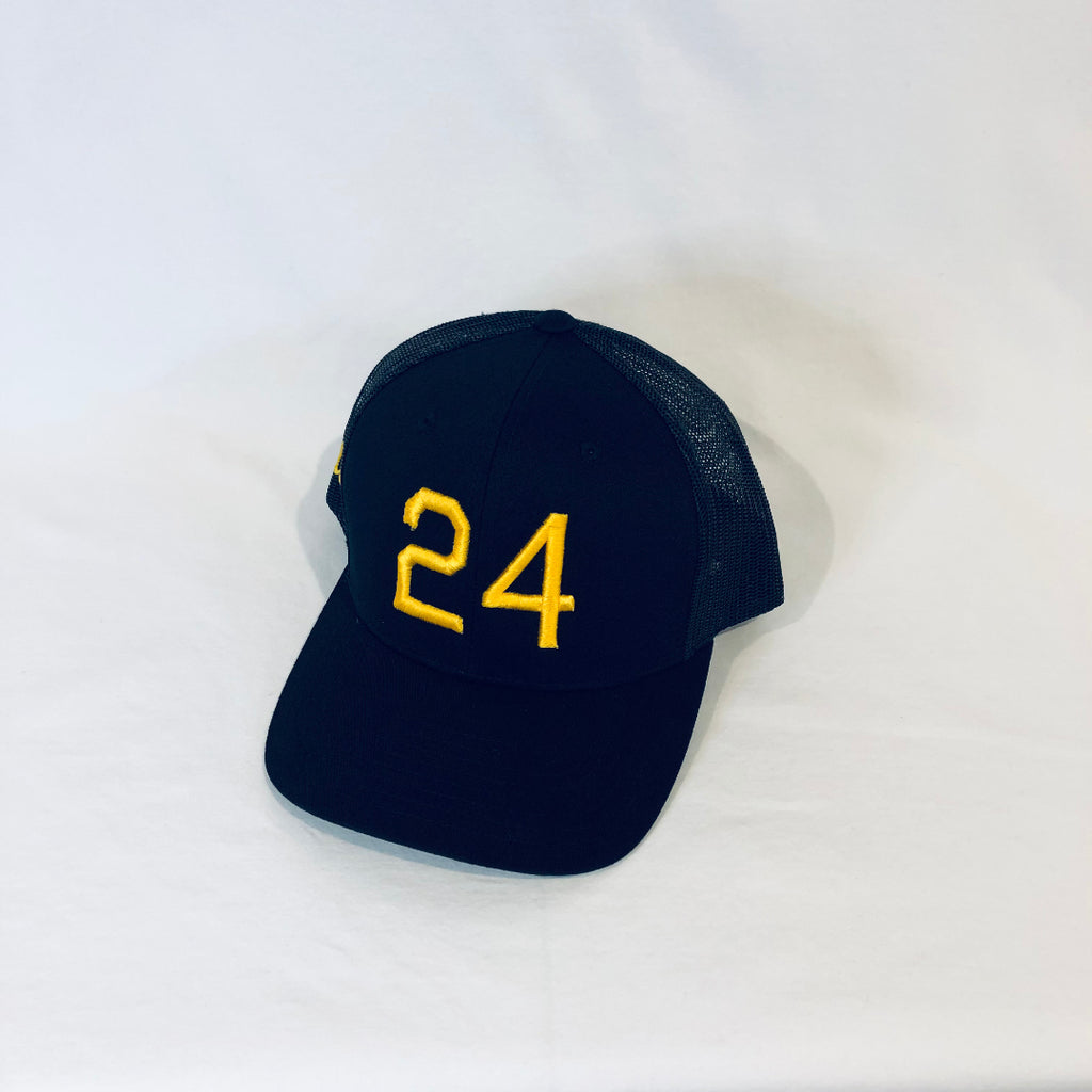an all black trucker hat with 24 in gold puff embroidery on the front