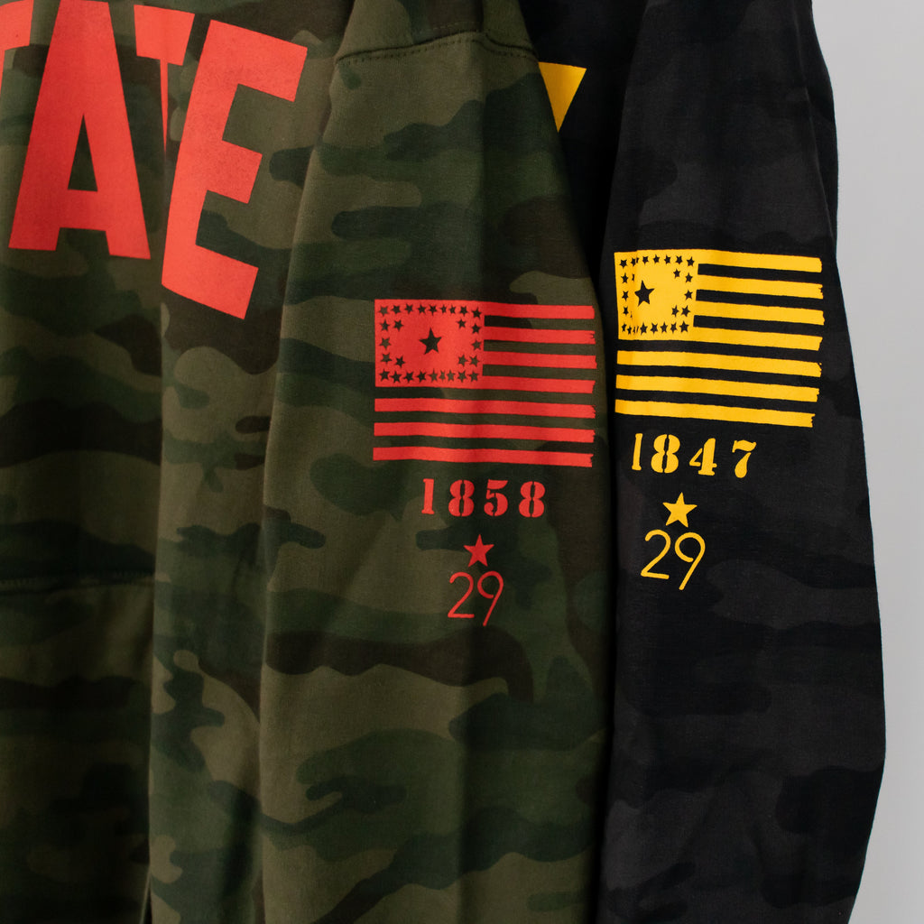 two camoflauge military inspired hooded sweatshirts focus is on the left sleeves of both showcasing the 29 star flag from the year 1846 under the flag is each schools established year and the 29th state apparel logo