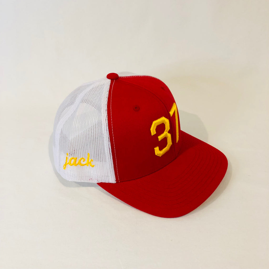 red and white trucker hat with 37 in gold on the front and jack in cursive gold lettering on the right side