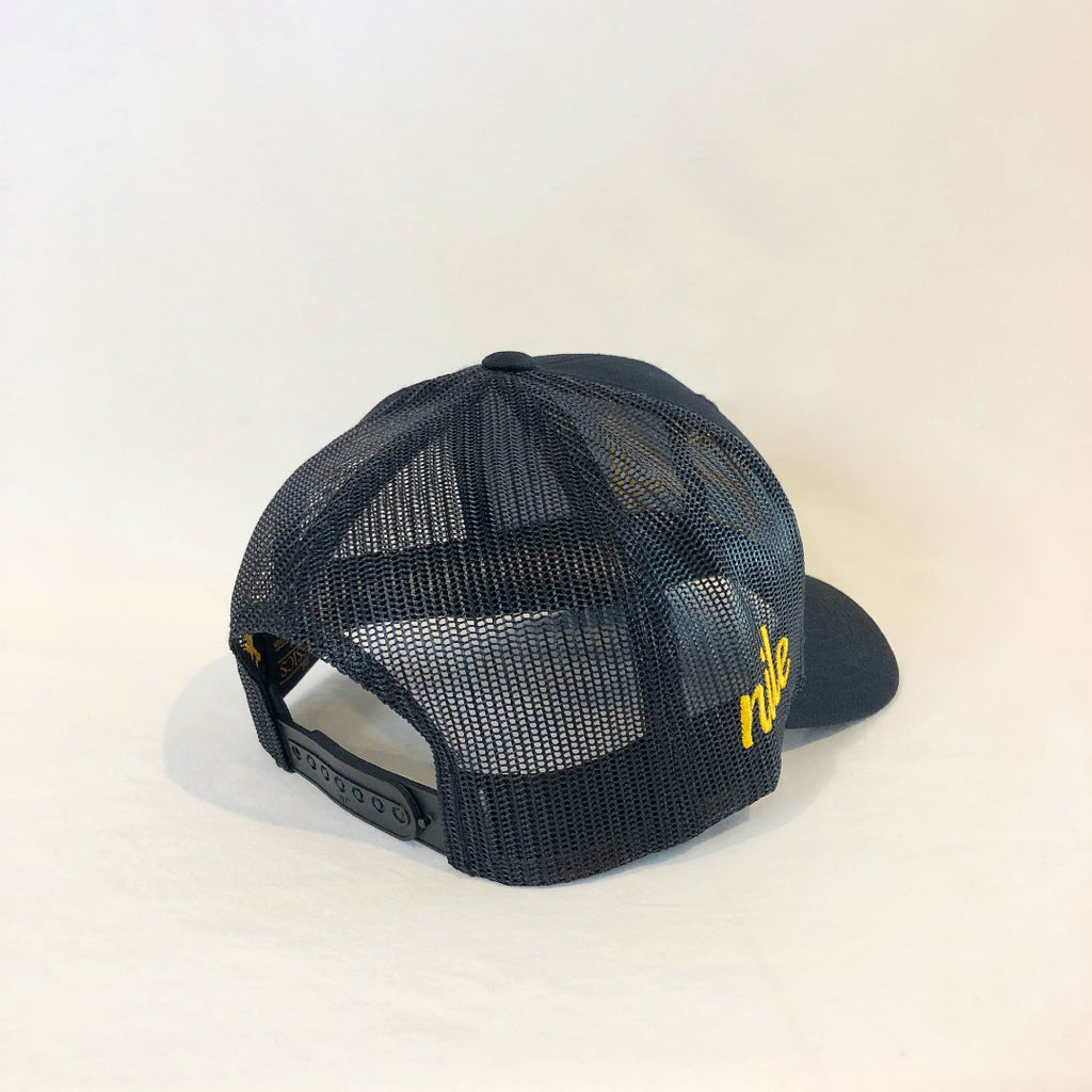 an all black trucker hat with a meshback nile in cursive gold lettering on the right side