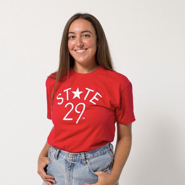 bronde model wearing a red tee with 29th state apparel logo in white on front center