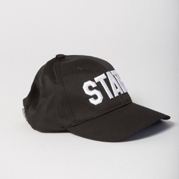 side view of black baseball hat with STATE embroidered on the front in white